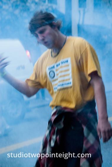 2015 Seattle May Day Protest Riot, Near Dusk, A Protester In A Cloud of Smoke and Tear Gas Cowered From A Stun Grenade Blast
